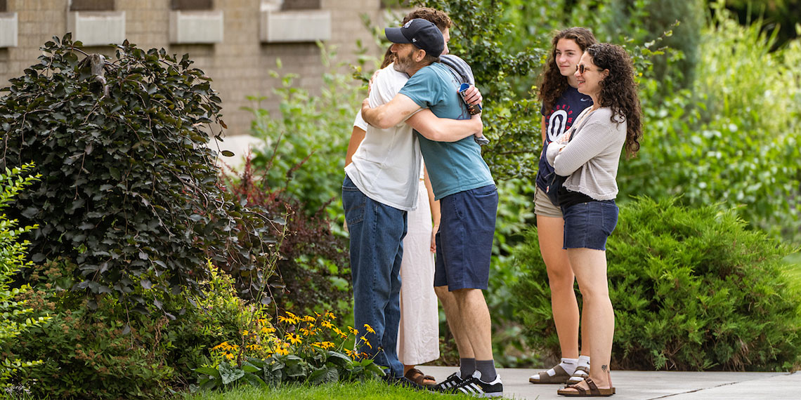 A man hugs his son as mom and sister look on