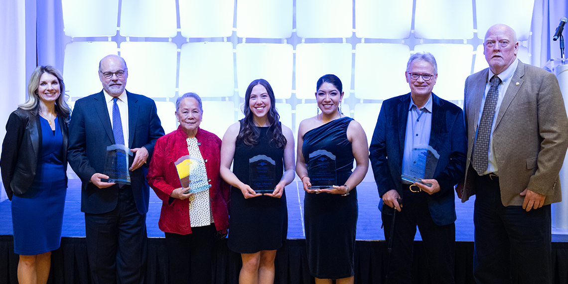 Seven people stand, five hold awards