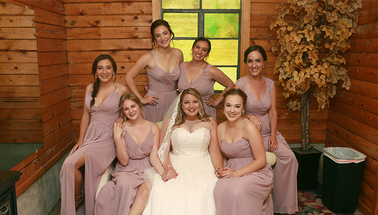 Bride sits surrounded by six bridesmaids. 