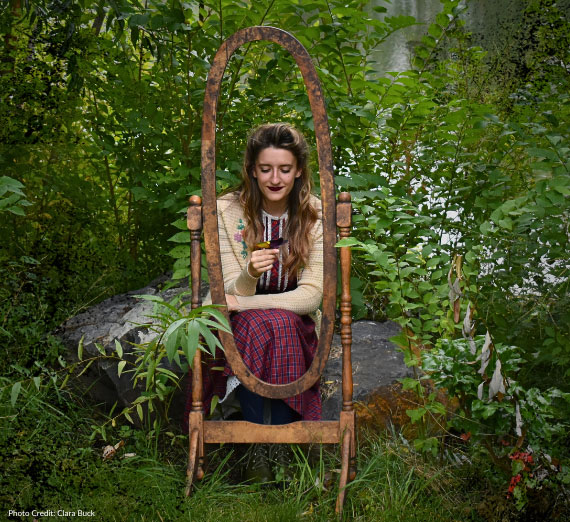 A woman kneels surrounded by plants