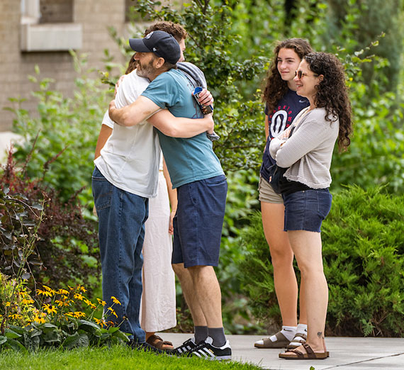 A man hugs his father as his mother and sister look on