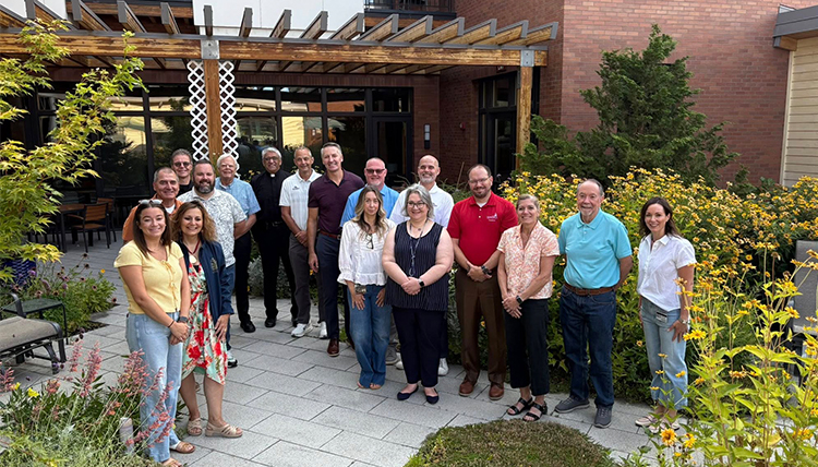 a group of men and women meet outside a residence in the summertime