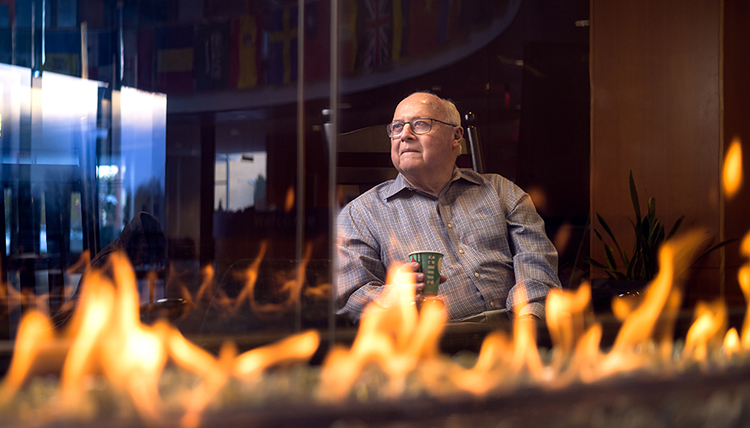 professor drinks coffee by fireplace