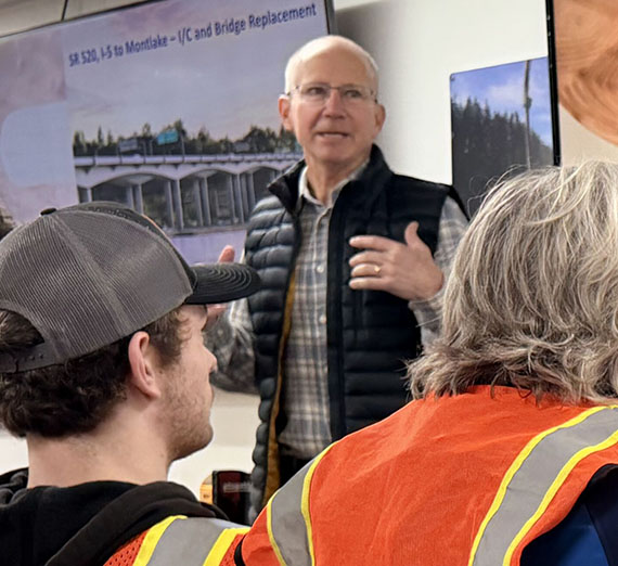a man speaks to people wearing safety vests