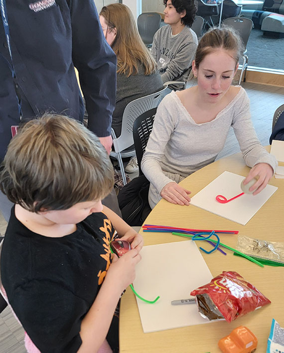 Gonzaga student and child bending craft pipe cleaners