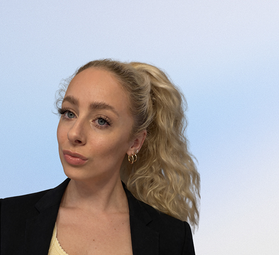 A female student in graduation cap and gown holds her degree over her head. 