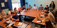 Students around a large table in classroom setting.