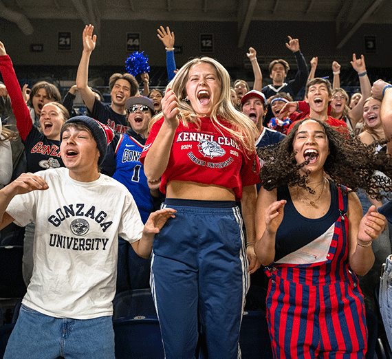 A woman jumps and cheers in a crowd of students