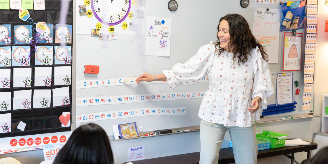Student teacher points at numbers in front of classroom of children