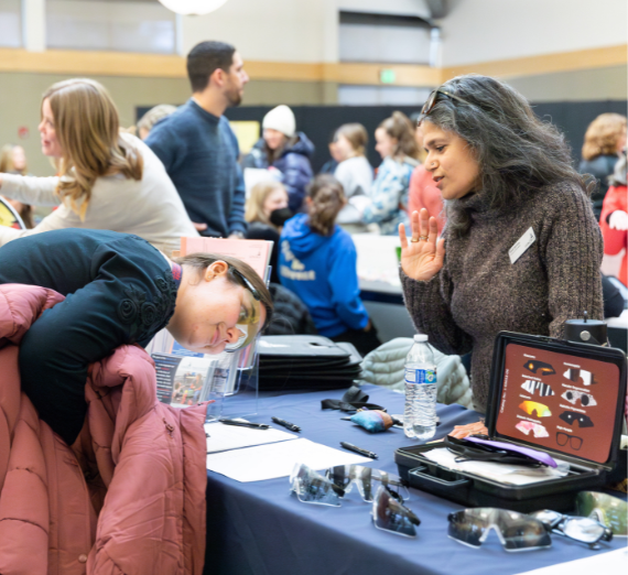 Faculty member shows person what visual impairment feels like through disability glasses
