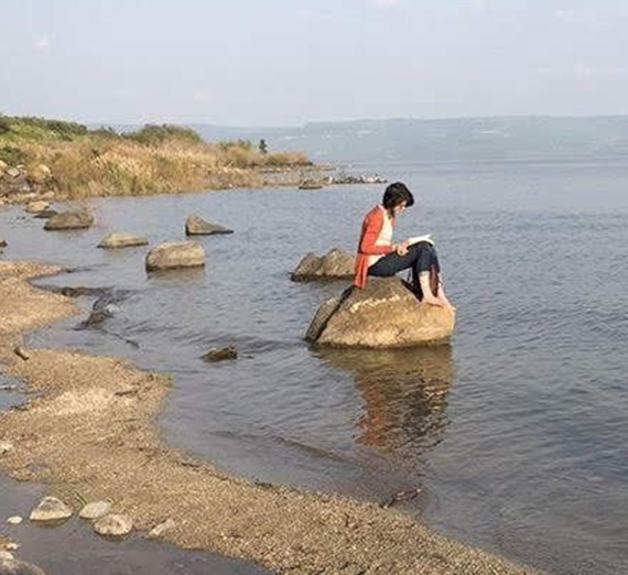 woman on rock at shore of sea of galilee 