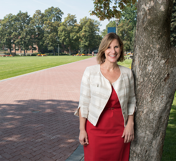 woman in dress next to tree on campus