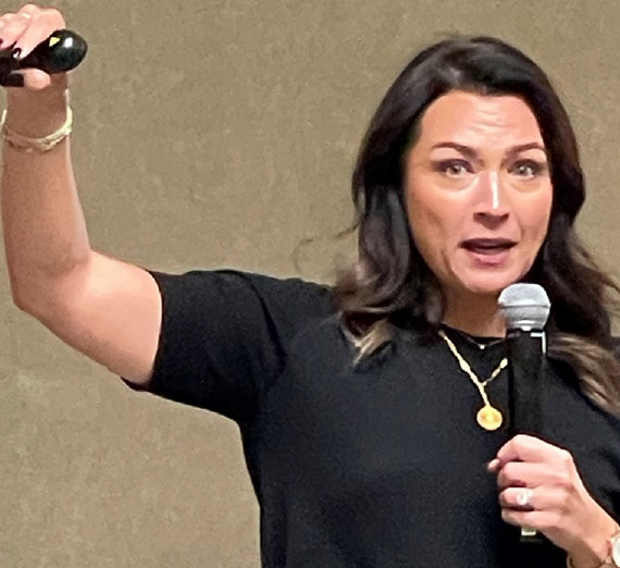 Woman holding a microphone while speaking. 