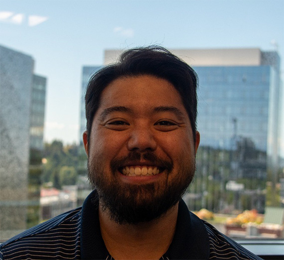 Master of Accountancy almunus David Togami in a striped polo in front of a window