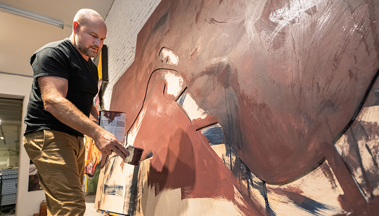 Artist Ben Joyce painting on a large canvas