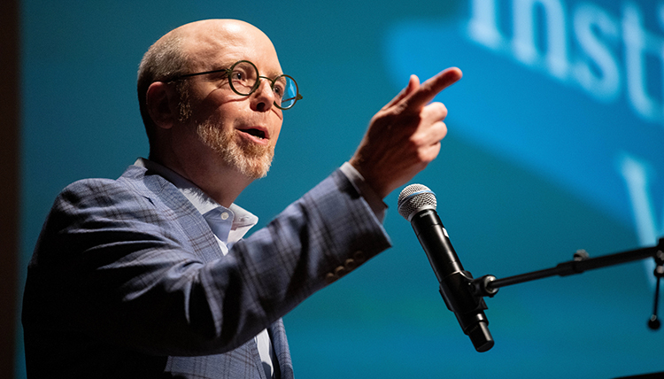 A man at a microphone points his finger
