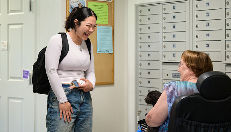 A standing woman talks to an older woman in a wheelchair
