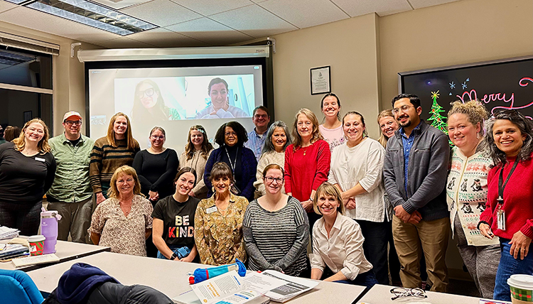 A group of people stand in front of a screen in a classroom