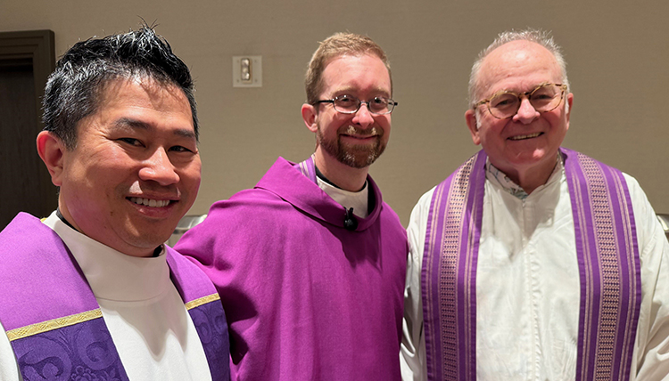 Three priests stand together purple robes.