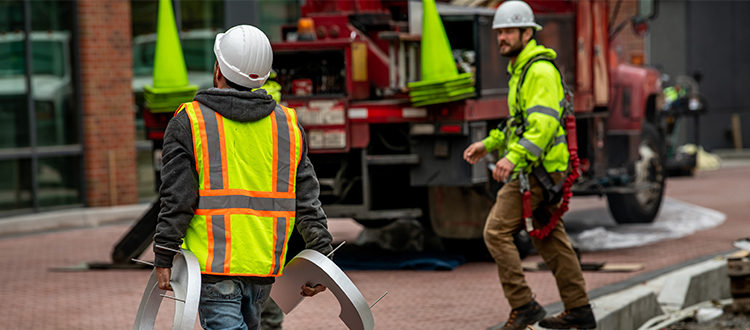Two construction workers walking towards a building.
