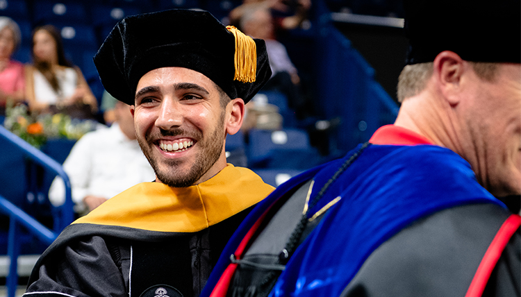 A smiling graduate 51�Թ� at Commencement.