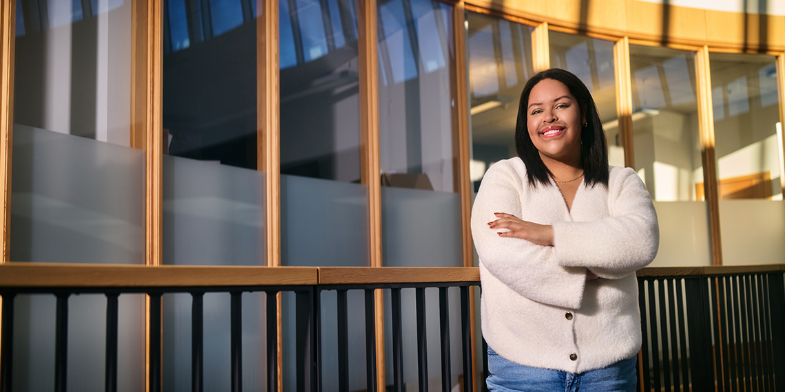 A woman with her arms crossed leans against a railing