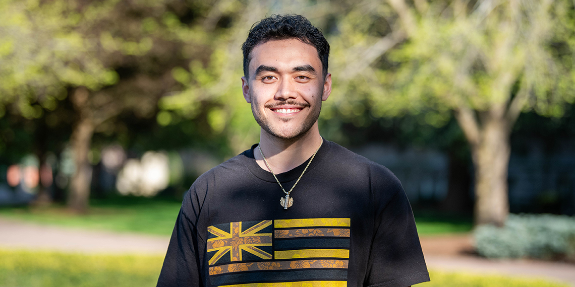A man with a mustache wearing a t-shirt and necklace