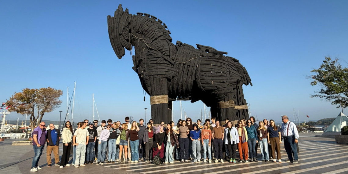 Dr. Andrew Goldman of the Gonzaga University History Department with a student group in front of a life-sized Trojan Horse.