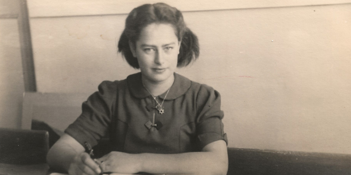 Woman sits holding a pencil. 