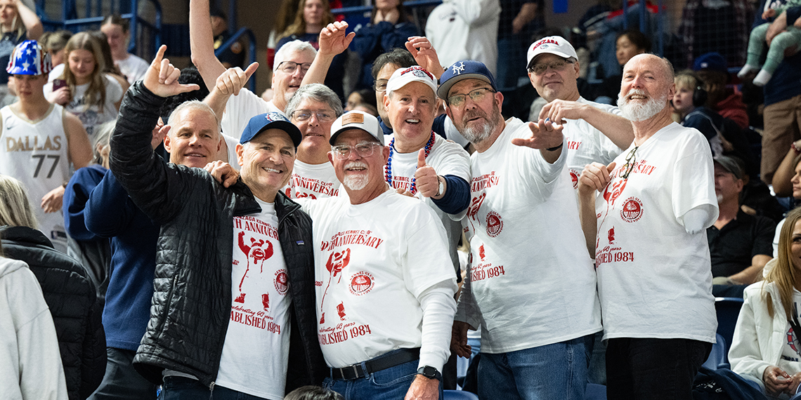 Group of men smile and wave at camera.