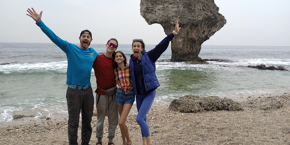 Family stands on a beach.