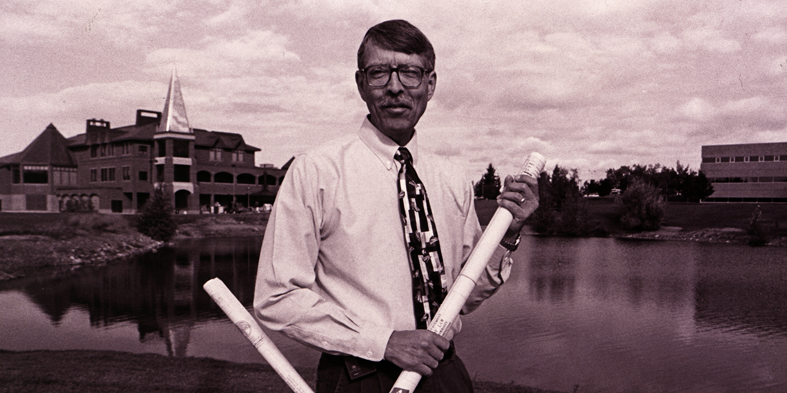 Sammons stands in front of campus building.