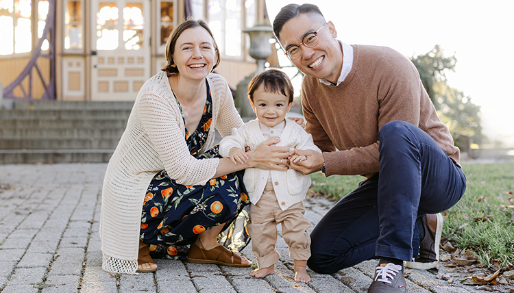 A couple smiles holding their baby.