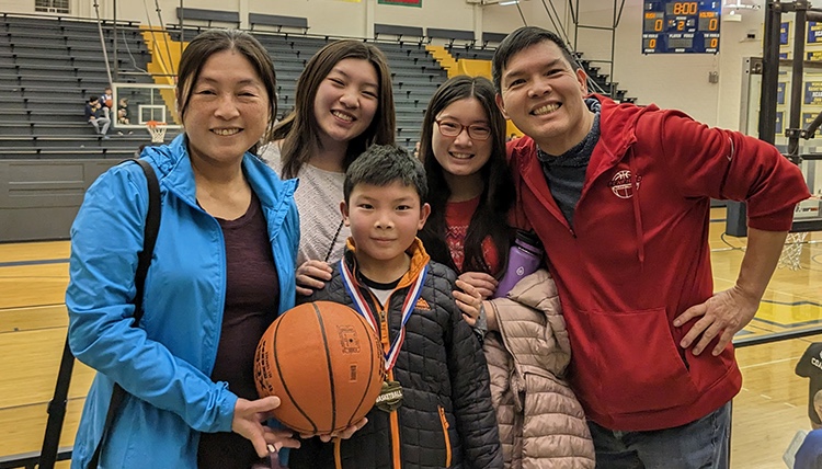 Jay Yang posing with family on basketball court