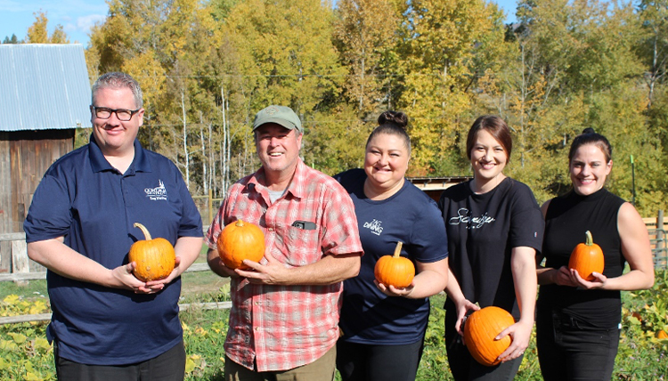 A group of people holding pumpkins and smiling 
