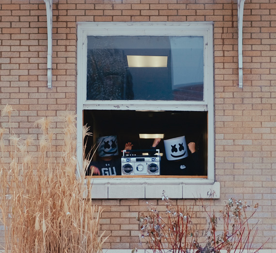 DJ DeSmet wearing marshmallow mask holding a jukebox out the DeSmet third story window.