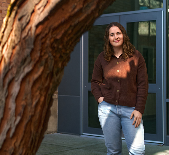 A woman stands with one hand in her pocket outside a door