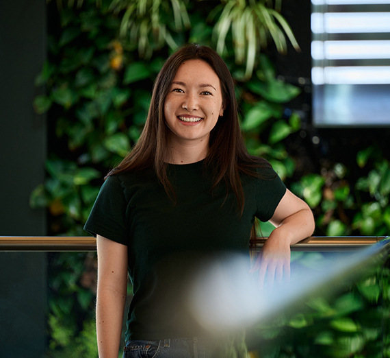 a woman stands in front of some plants