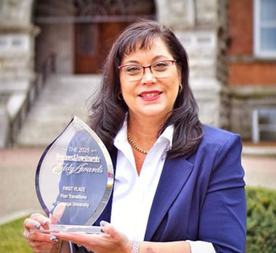 A woman with long dark hair and glasses holds a trophy made of glass