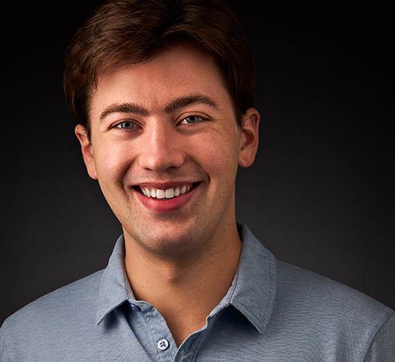 A smiling man in a blue-collared shirt