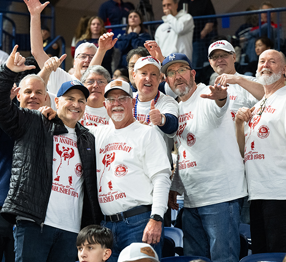 A group of guys smiles and waves at the camera. 