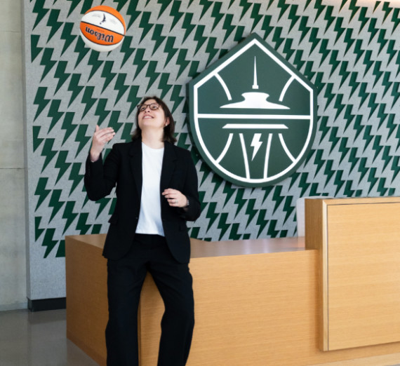 Olive in front of the Seattle Storm logo with a basketball