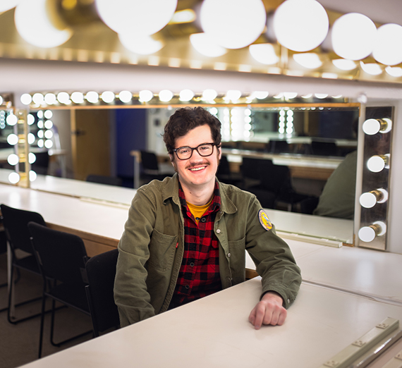 Pete King sits in front of mirrors surrounded by light bulbs