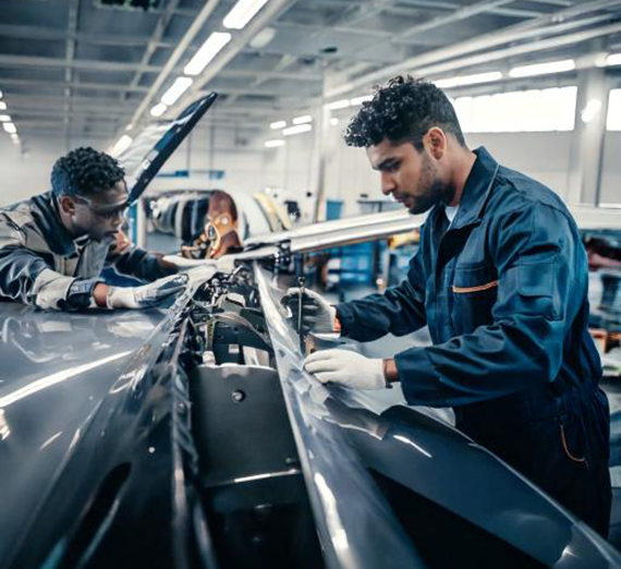 Two workers adjust a plane wing in a manufacturing plant