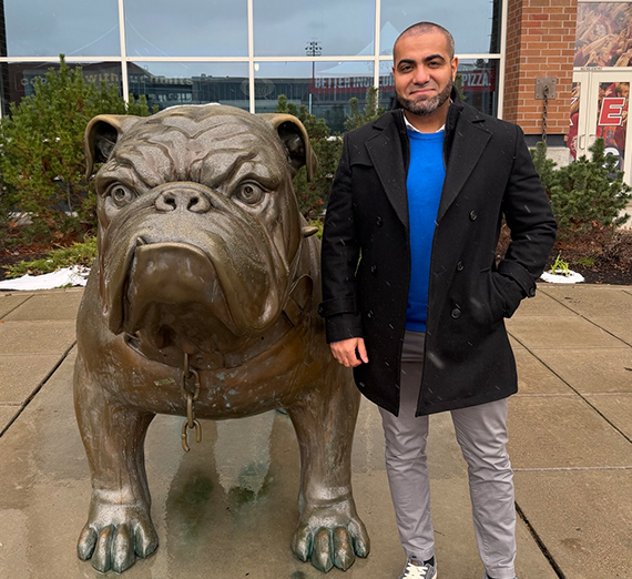 Man standing next to a bronze bulldog.