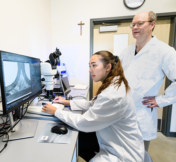 A professor and student look at a computer screen in a laboratory