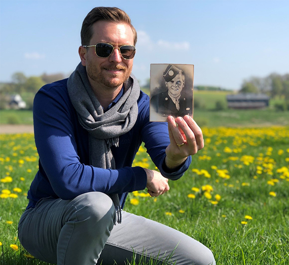 man holds photo of solider in field