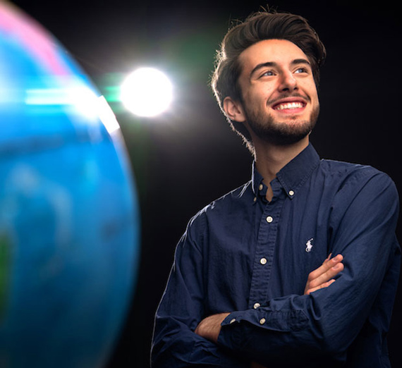 Gonzaga Senior Antoinne Herrbach, smiling next to close up of globe.
