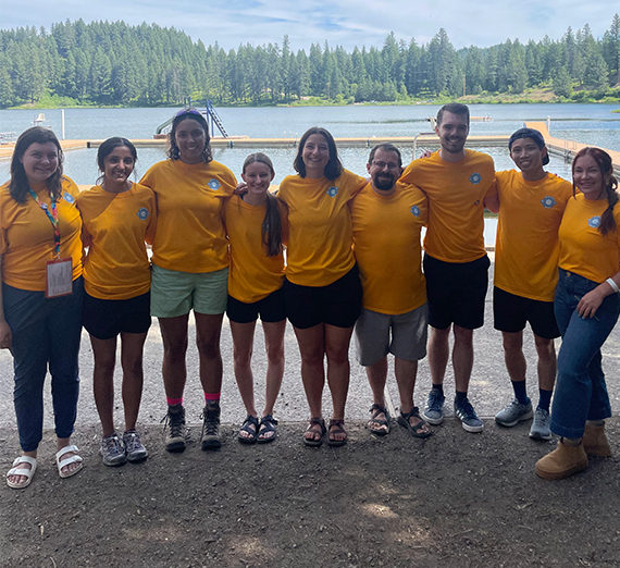 Picture of people wearing yellow shirts standing in a line on a lakeshore.