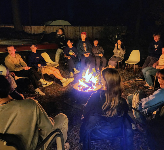 English 101 students gather around a campfire.